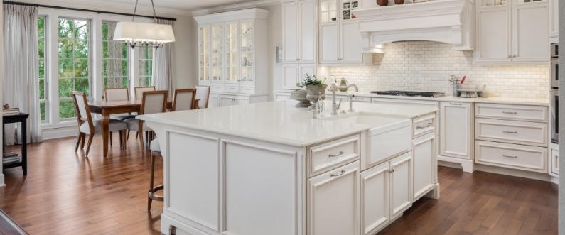 photo of a kitchen with white cabinetry, medium tone wood, and an open concept dining room