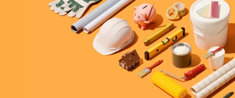various remodeling tools and a piggy bank laid out on an orange background